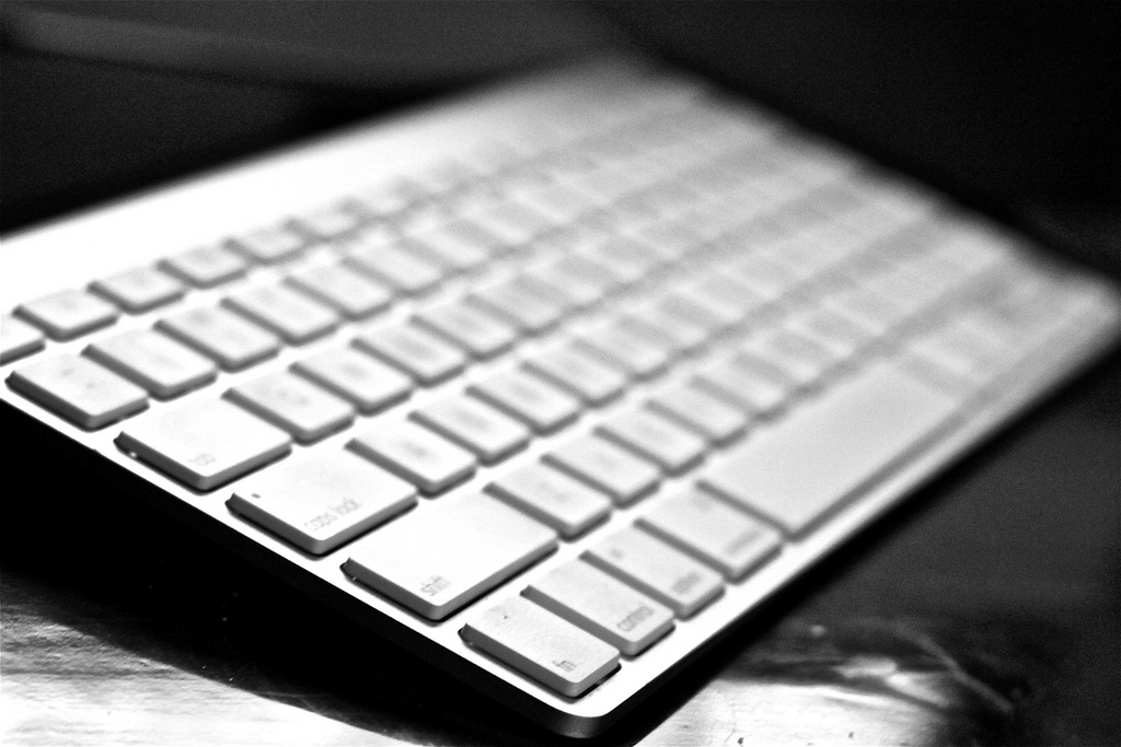 A close-up black and white image of a computer keyboard on a desk.