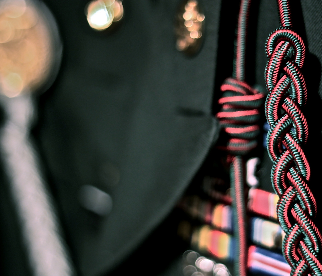 This is an artistic image that shows a very close up photo of a soldier's dress uniform jacket, focusing on the service ribbons and other formal dress accessories on his jacket. 